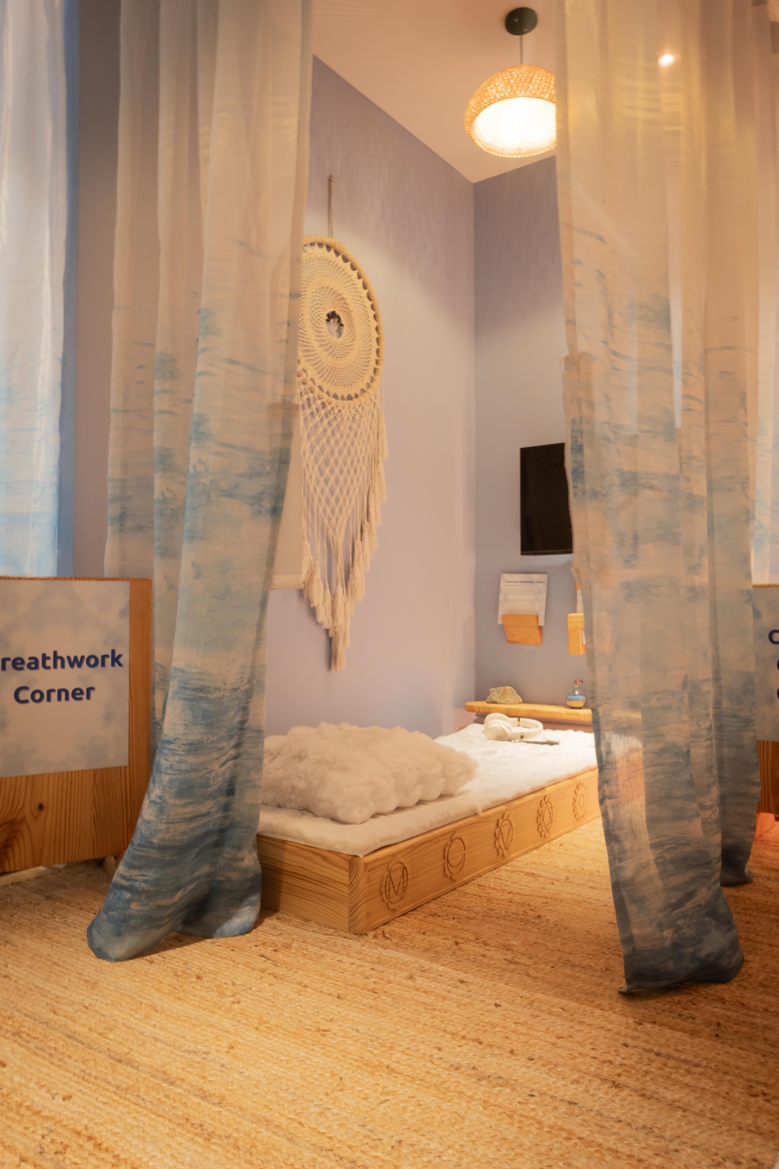 The Breathwork Corner: a low bed behind hanging curtains, headphones set out